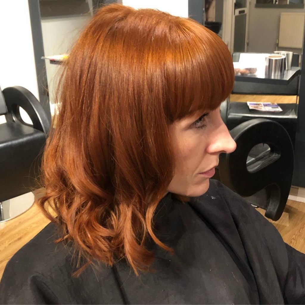 Frisuren mittellang: Frau mit rotem Longbob und Pony